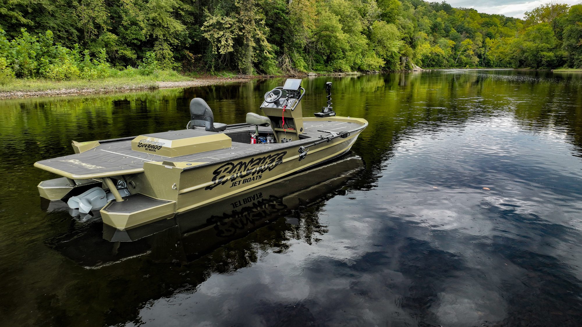 A green Banshee jet boat seen from the stern, reflected in still river water