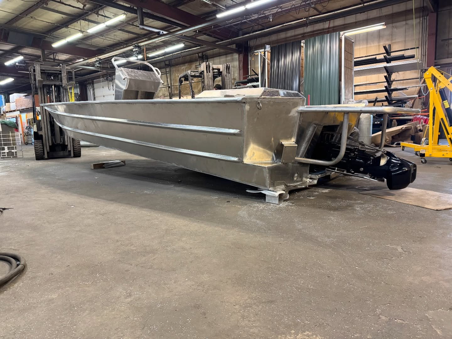 A bare aluminum Banshee hull in the shop, outboard jet mounted on the transom