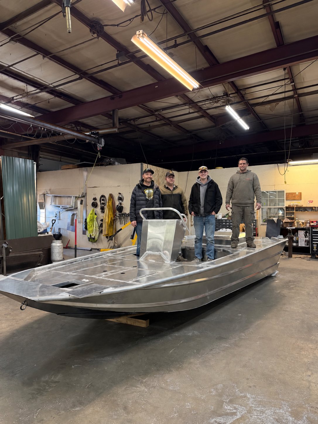 The Banshee crew in the shop, standing with a bare aluminum hull